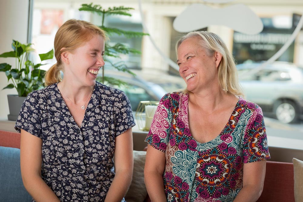 Två kvinnor kollar på varandra, de ler och skrattar tillsammans